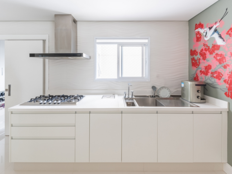 Cozinha com bancada branca, papel de parede cinza com flores rosas e janela branca 