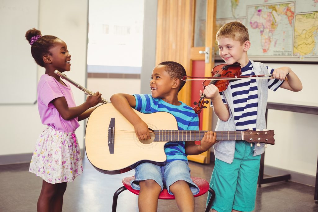 Três crianças, cada uma delas com um instrumento musical diferente; flauta, violoncelo e violão