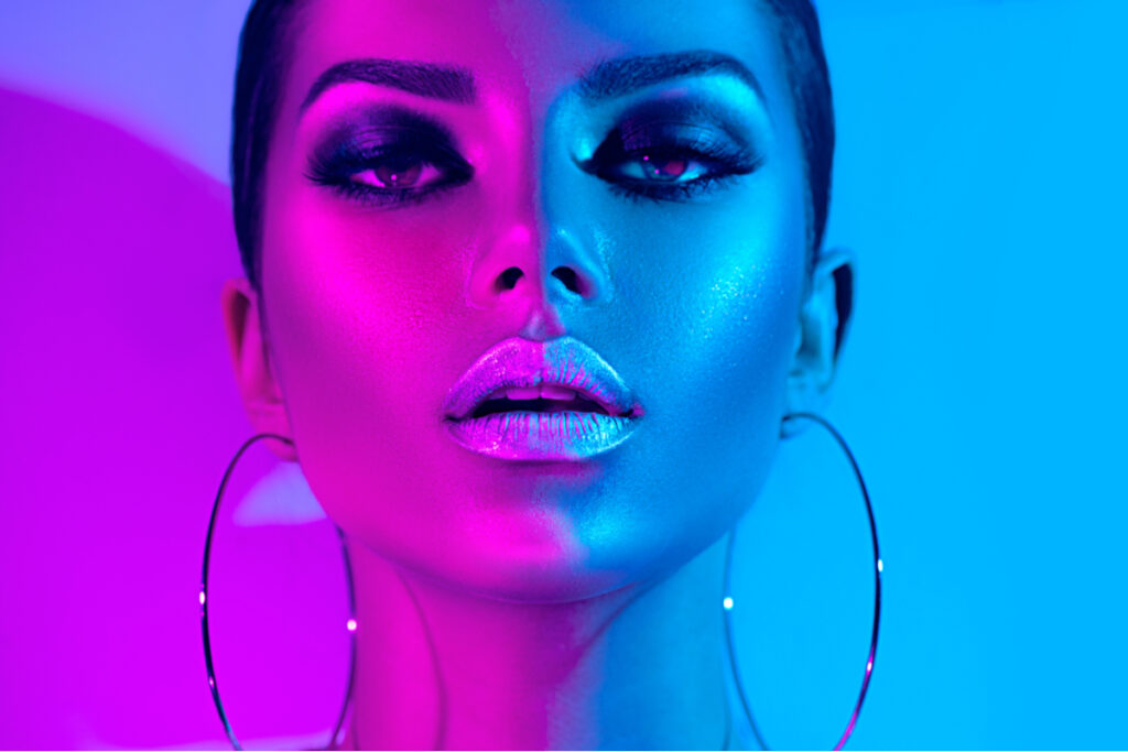 Modelo com maquiagem escura em luzes coloridas no tom de roxo e azul