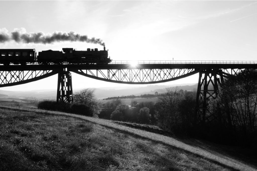 Imagem em preto e branco de um trem passando na linha férrea
