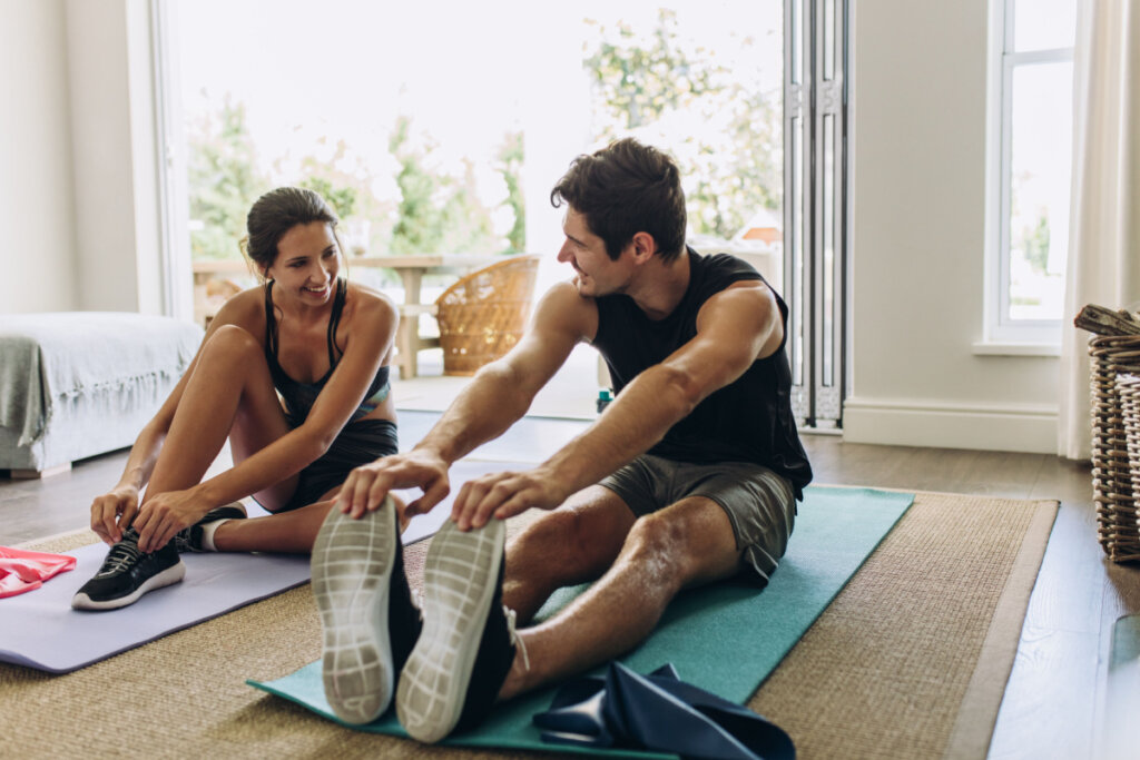 Homem e mulher em roupas esportivas fazendo exercícios em casa.