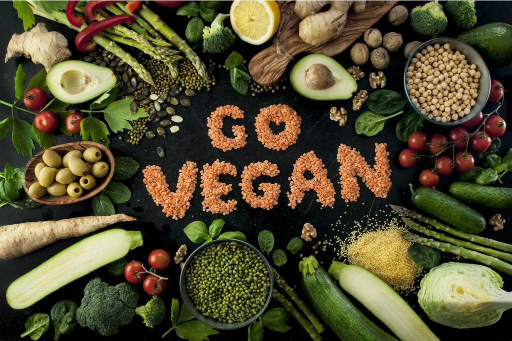 Imagem com "go vegan" escrito e alimentos saudáveis ao redor