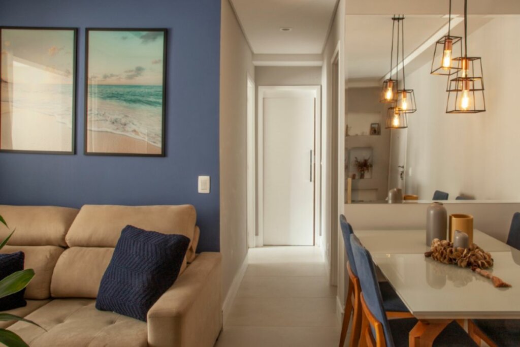 Sala de estar com parede azul e sofá bege integrada com a cozinha