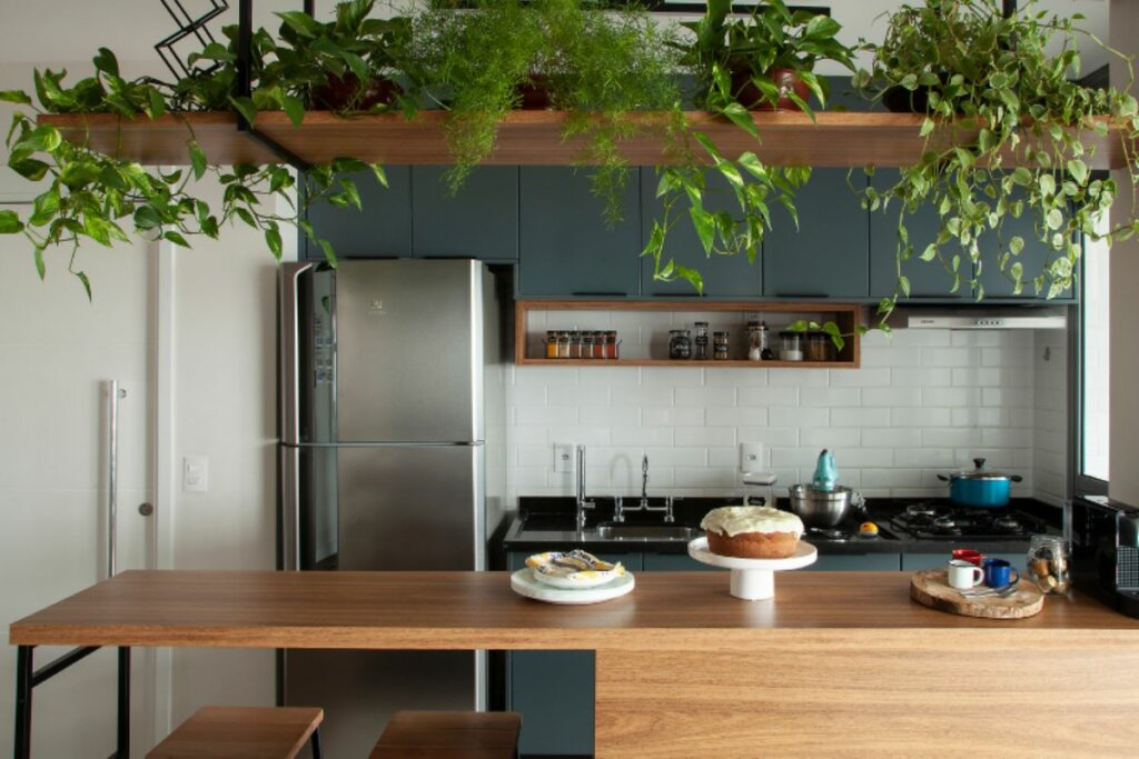 Cozinha com móveis de madeira, parede branca e plantas 