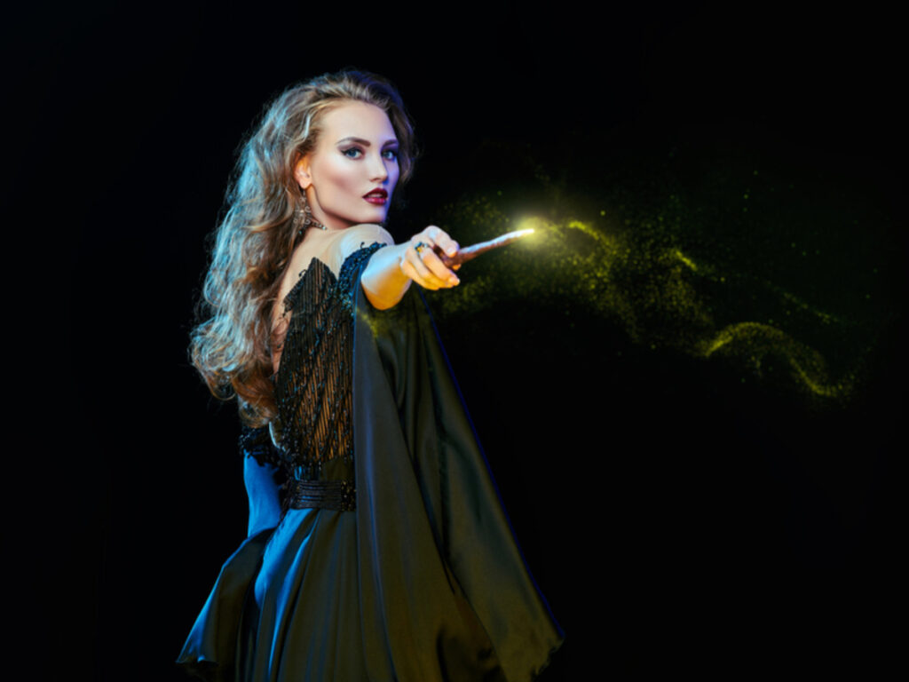 Jovem bruxa lançando feitiço com uma varinha mágica