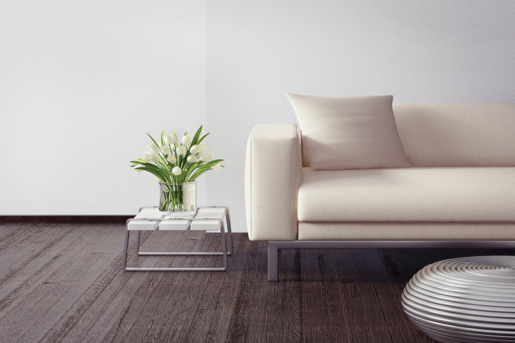 Mesa quadrada com um vaso de planta e sofá branco ao lado 