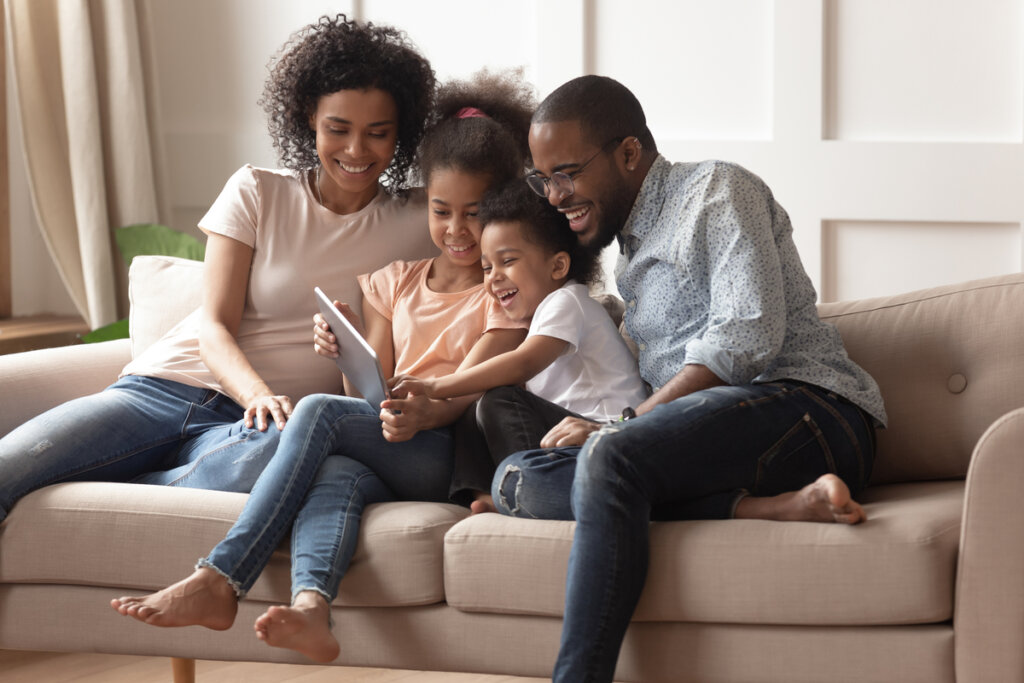 Família feliz se divertindo com tablet em casa