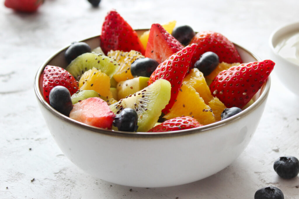 Bowl branco com frutas frescas. Morango, kiwi, laranja e mirtilo