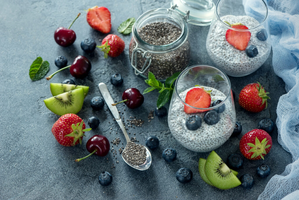 Mesa com frutas vermelhas e copos com iogurte natural com chia e decorado com frutas