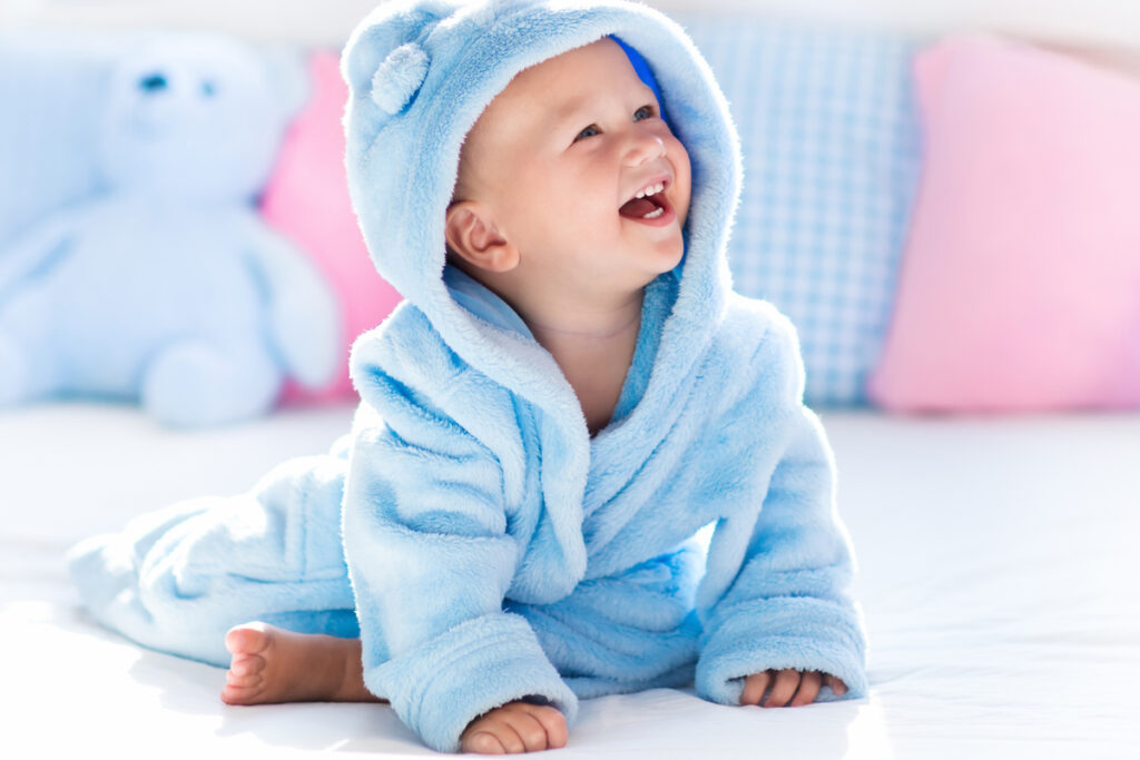 Bebê vestido com macacão azul sorrindo