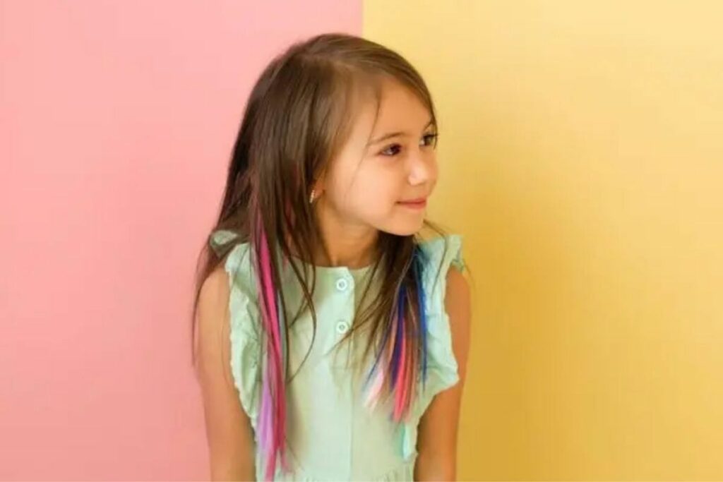 Menina de blusa e cabelo com mechas coloridas olhando para o lado e sorrindo