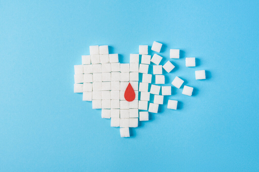 Cubos de açúcar em formato de coração se despedaçando e gota de sangue desenhda no meio