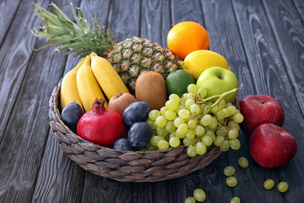 Recipiente com banana, abacaxi, uva, maçã, laranja e outras frutas