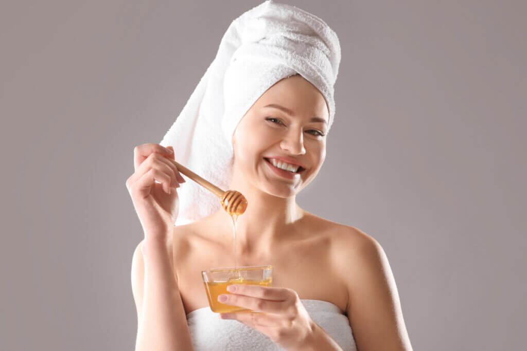 Mulher apenas de toalha segurando um pote de mel