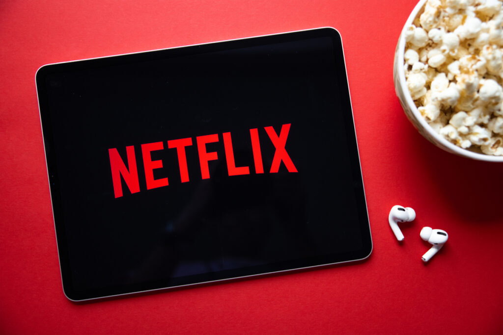 Tela de tablet aberta na Netflix, em fundo vermelho e com balde de pipoca ao lado