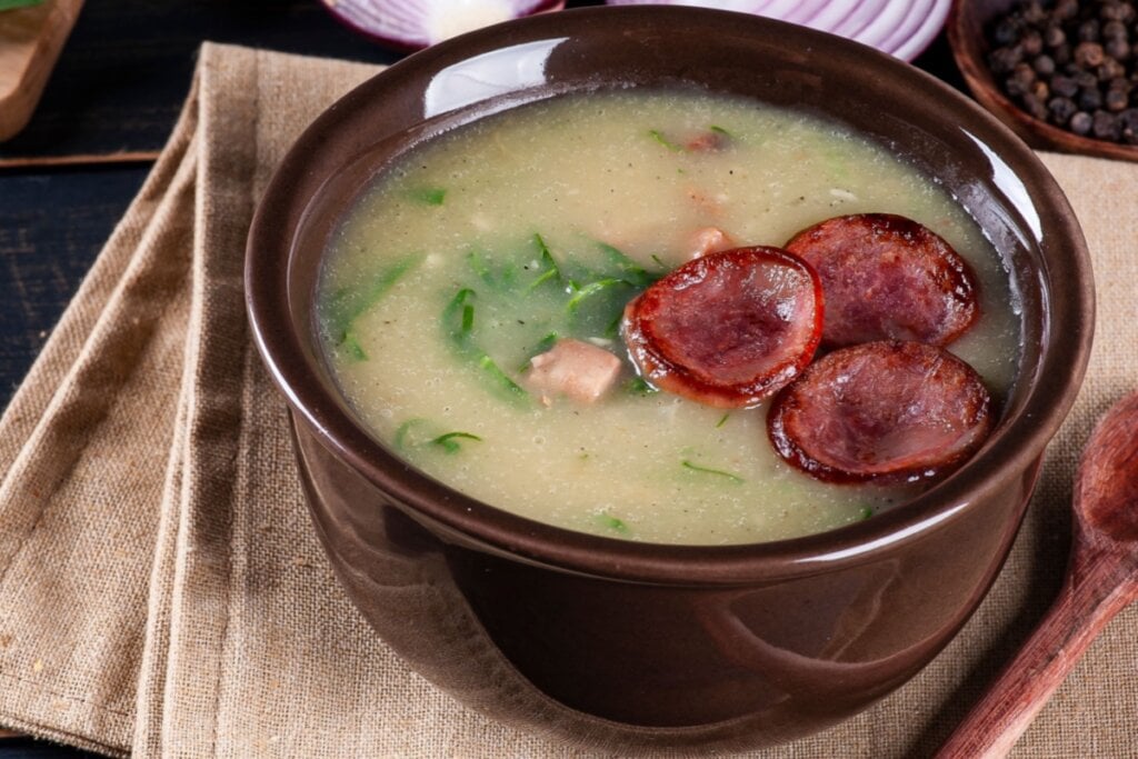 Recipiente marrom com caldo verde com couve, bacon e linguiça calabresa