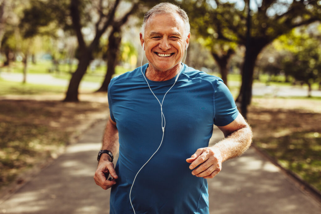 Homem de meia idade usando fone de ouvido e correndo em um parque