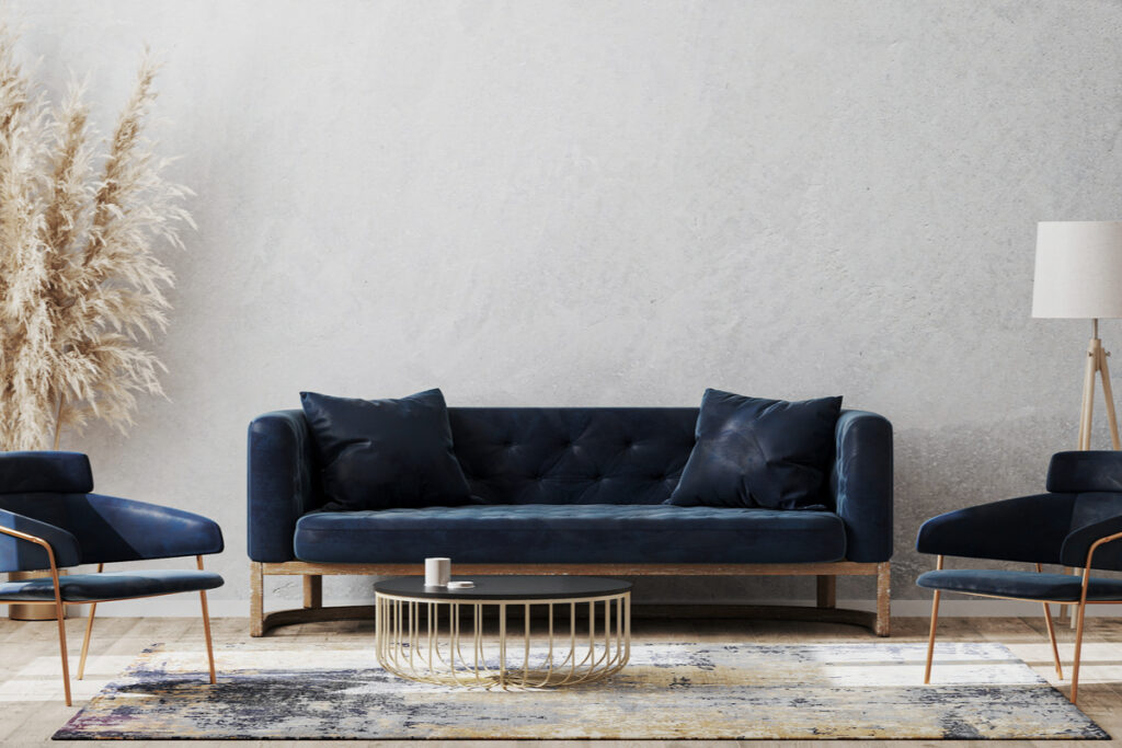 Sala de estar com sofá e poltronas azul escuro numa parede clara, quase branca