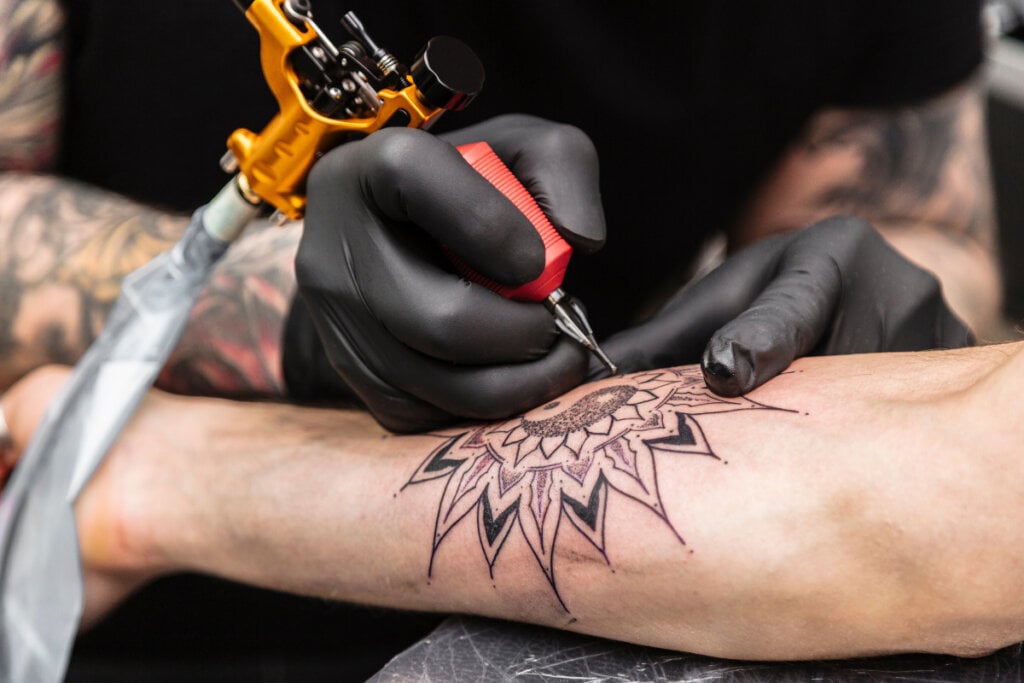 Tatuador fazendo mandala no antebraço de cliente