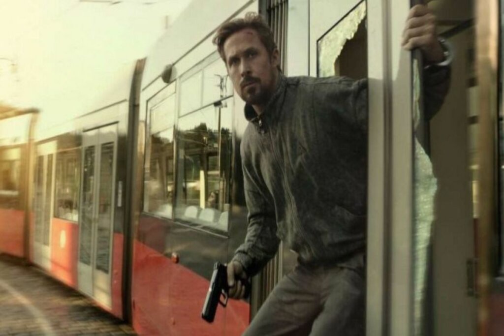 Personagem Court Gentry (Ryan Gosling) armado e pendurado em um trem