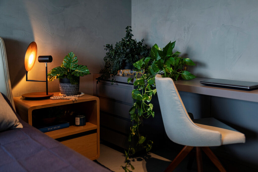 Quarto com móveis de madeira, cadeira branca e vasos de plantas 