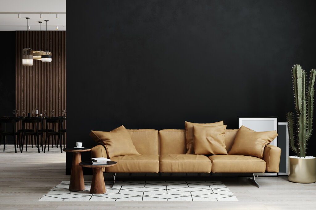 Sala de estar com parede preta, sofá marrom e vaso com cacto