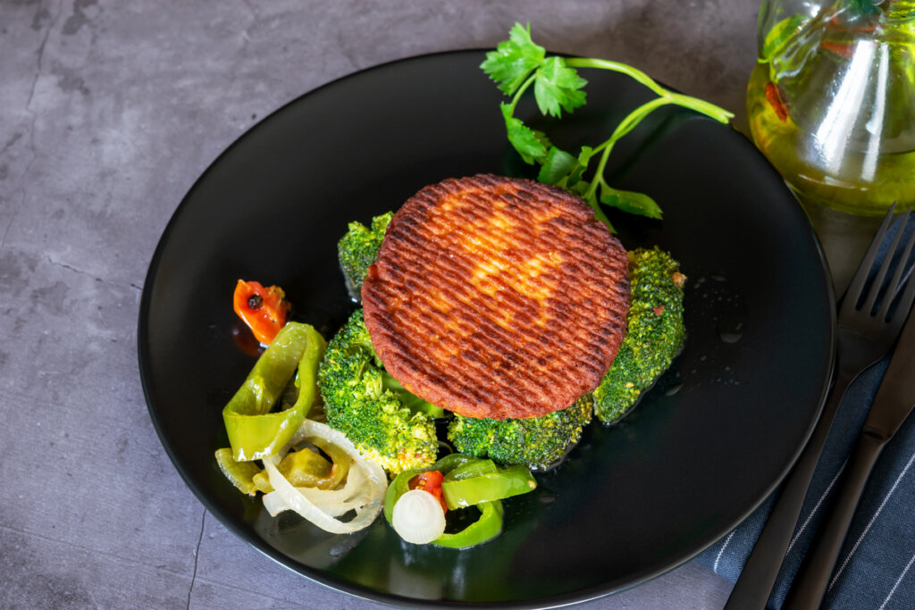 Hambúrguer de salmão em prato acompanhado por salada