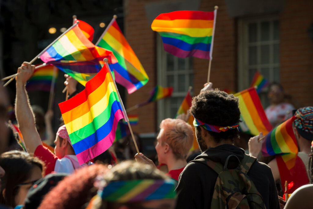 Pessoas com a bandeira da comunidade LGBTQIA+