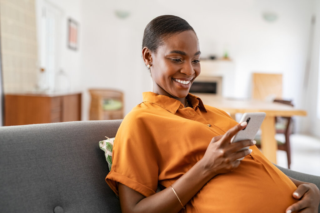 Mulher grávida sentada mexendo no celular