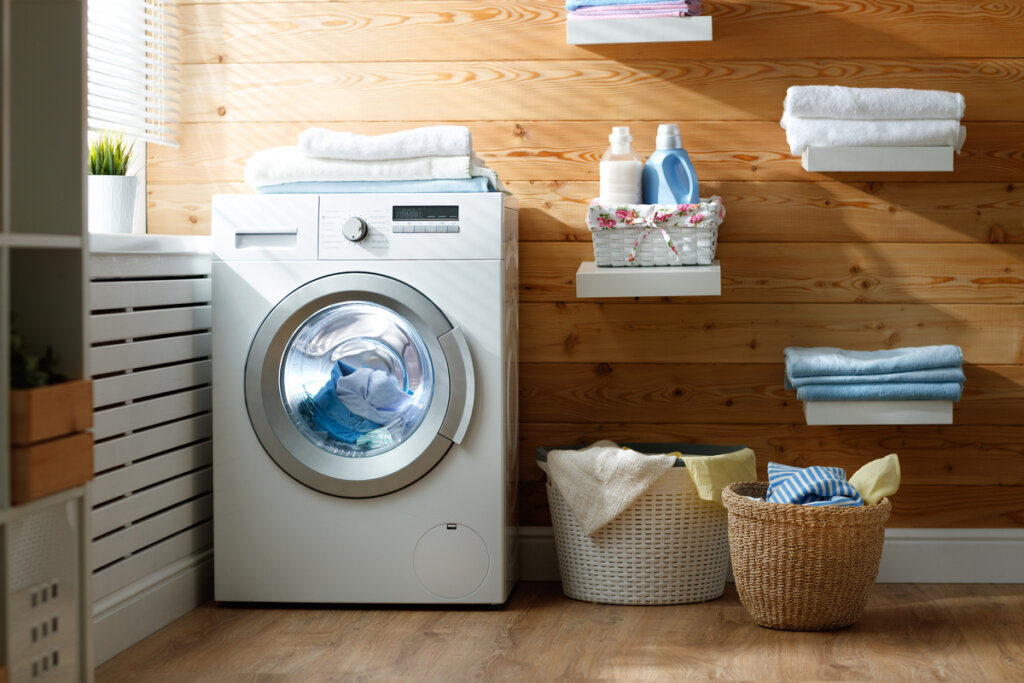 Lavanderia com máquina de lavar branca e cestos de roupa 