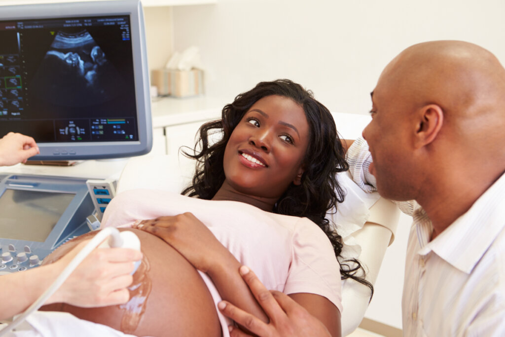 Casal se olhando durante realização de ultrassom na mulher, que está grávida. 