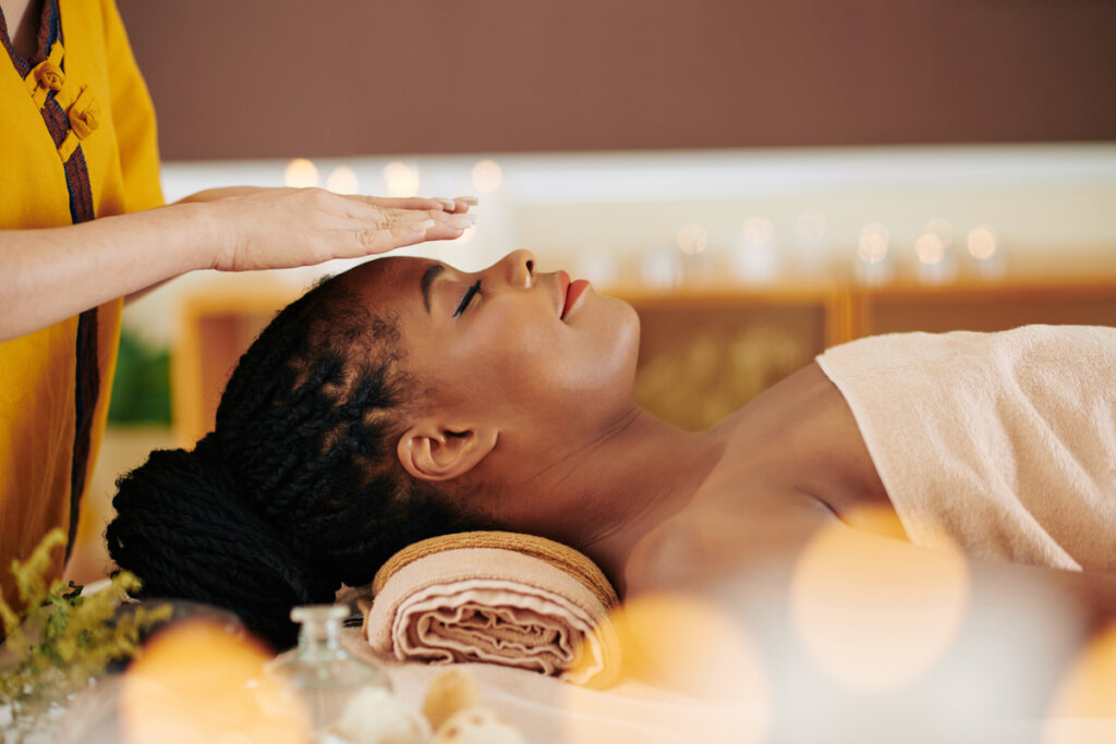 Terapeuta aplicando a prática de reiki em uma mulher deitada