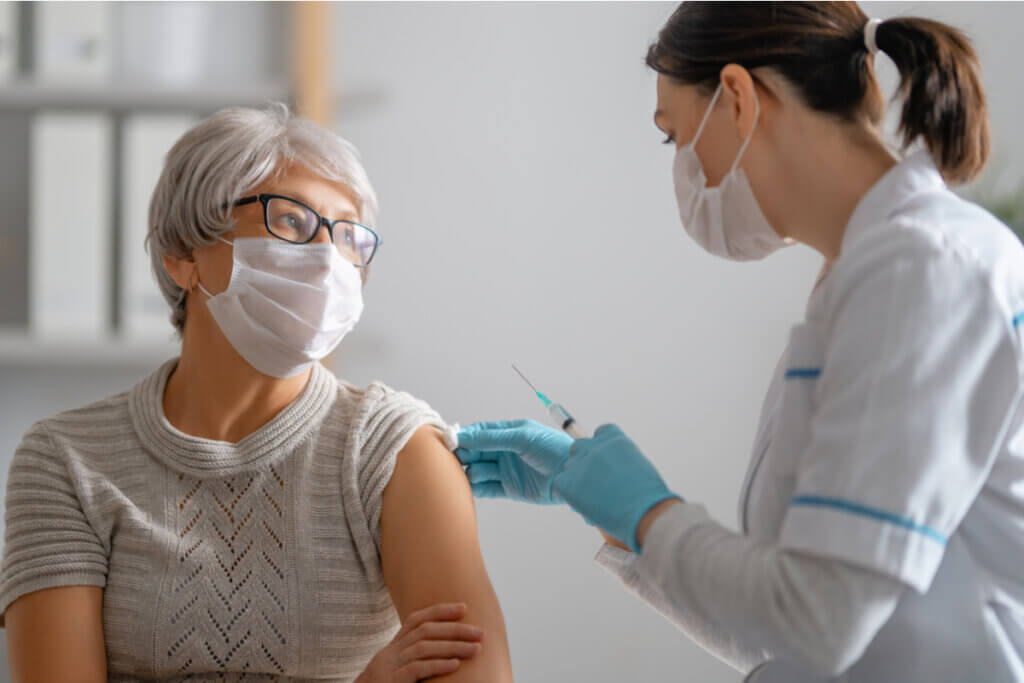 Enfermeira limpando o braço de uma mulher para aplicar vacina