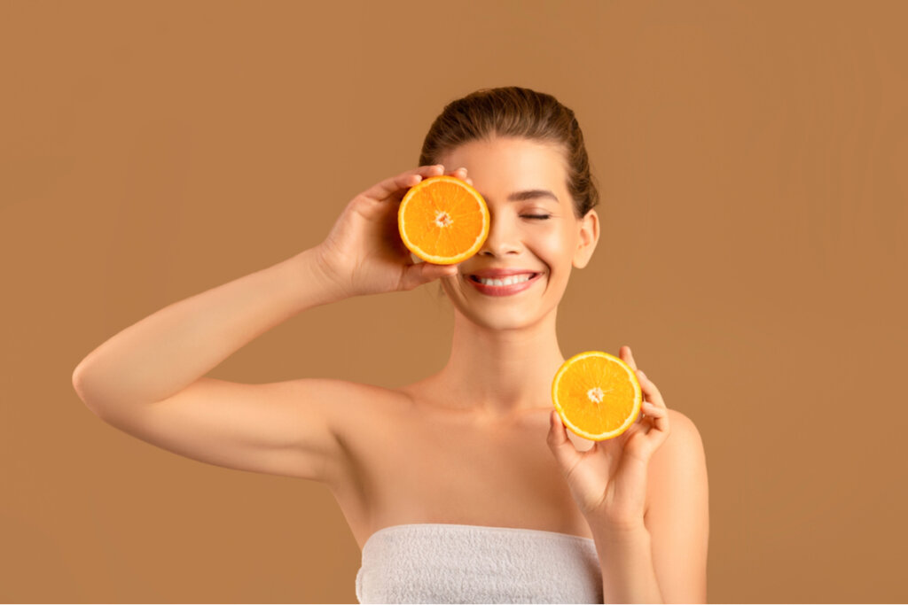 Mulher segurando duas laranjas na frente do rosto