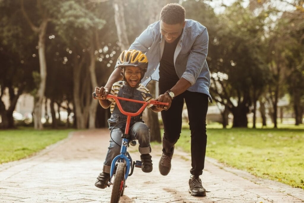 Pai ensinando o filho a andar de bicicleta em parque