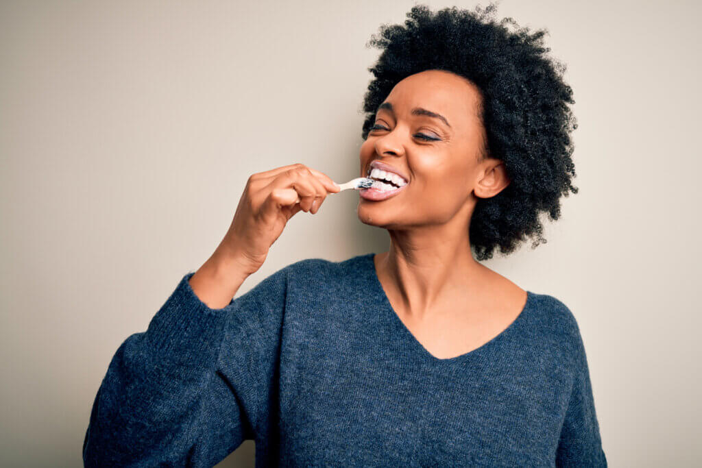 Mulher sorrindo escovando os dentes