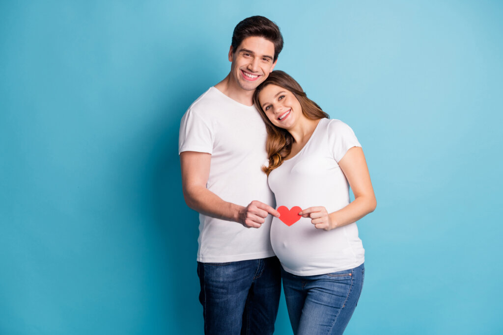 Homem e mulher grávida segurando um coração