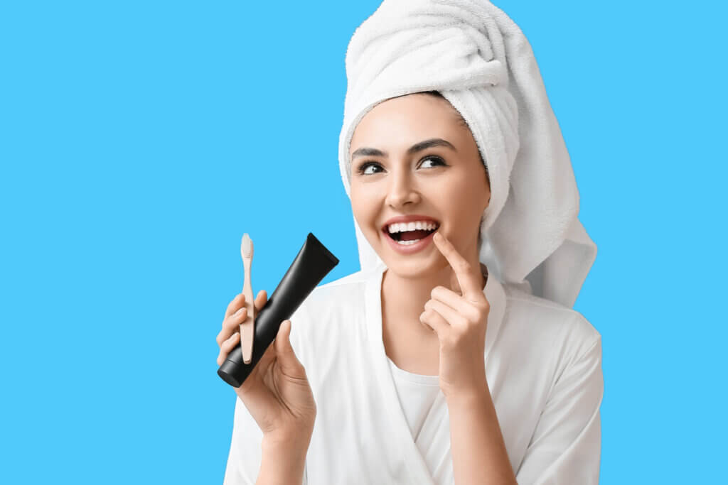 Mulher sorrindo com escova dental e pasta de dente na mão