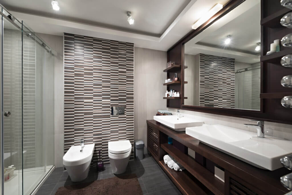 Banheiro com duas pias, espelho grande e armários em madeira