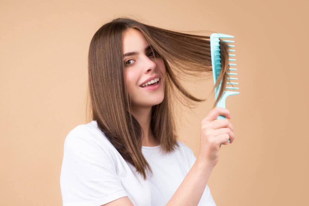 Mulher sorrindo segurando um escova no cabelo