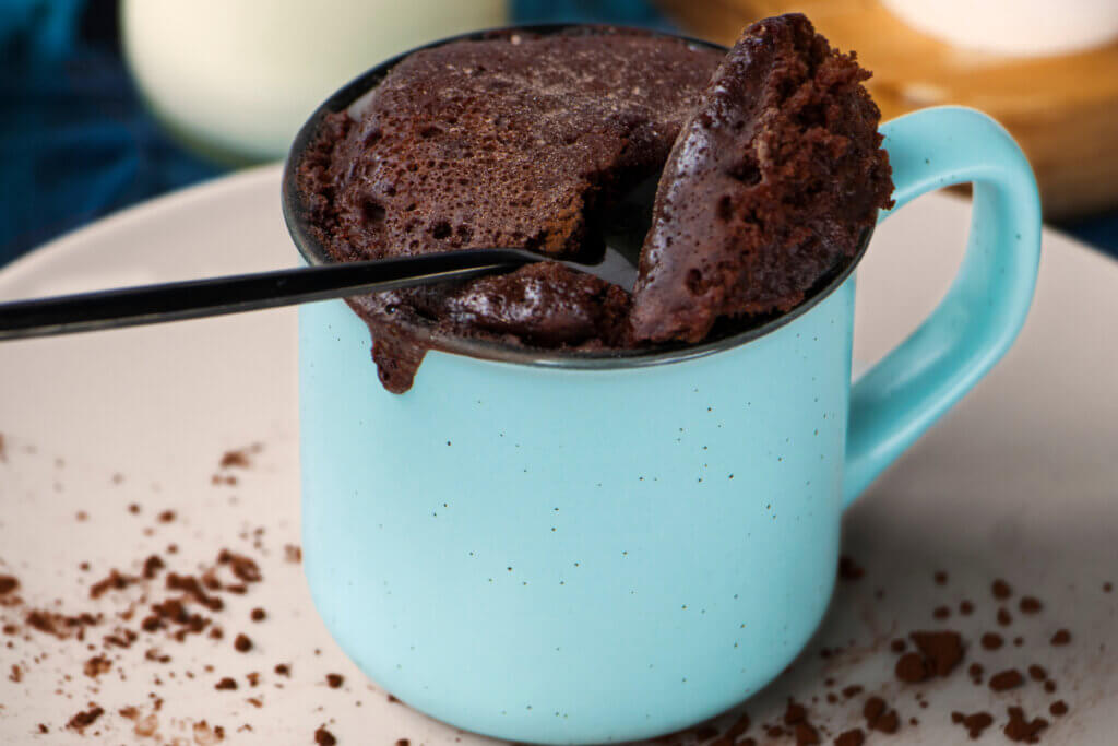 Bolo de chocolate em uma caneca azul com uma colher 
