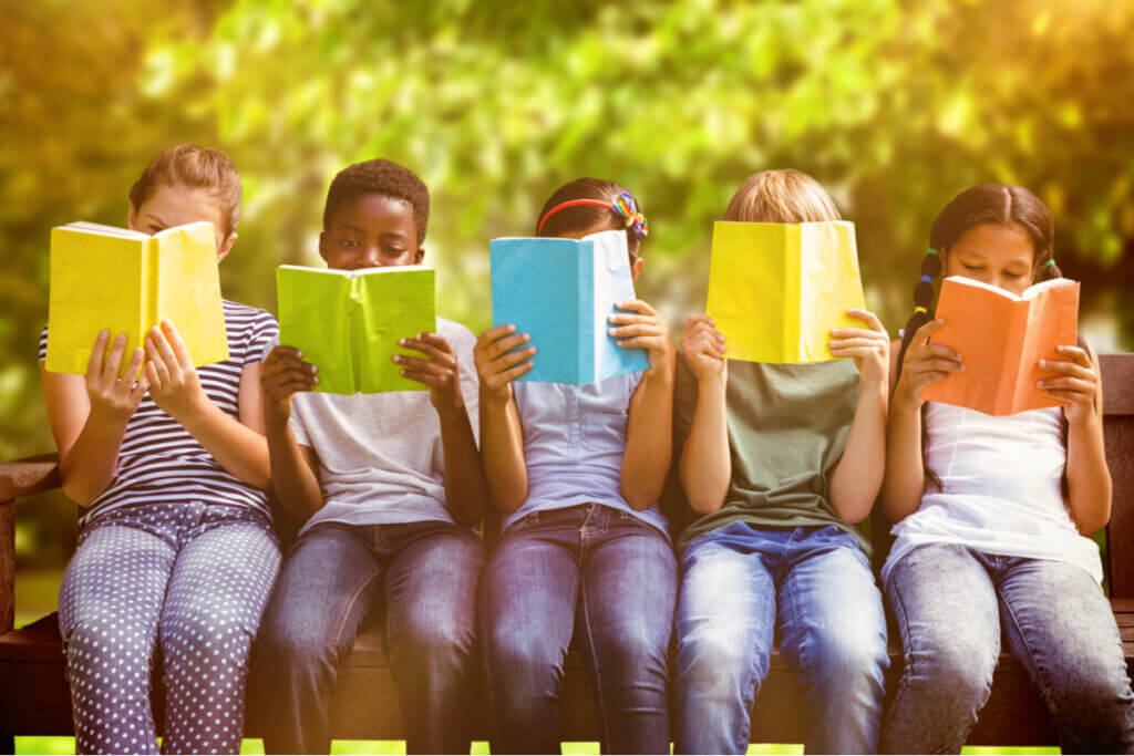 Crianças sentadas em parque lendo livros