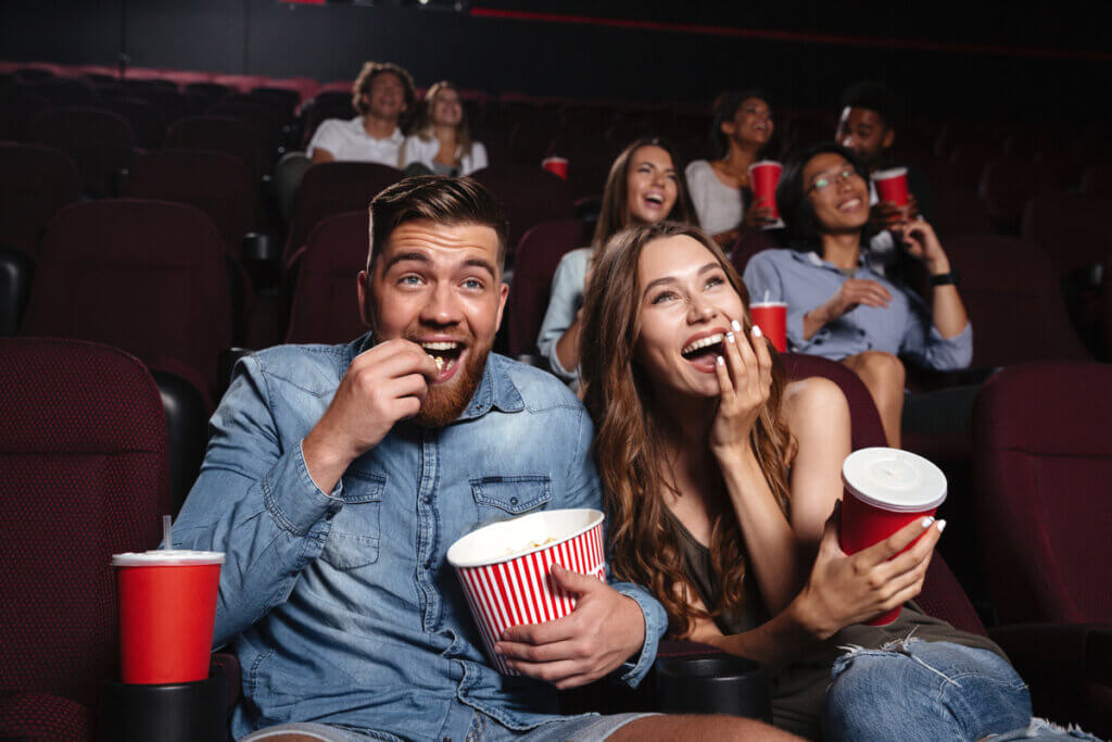 Pessoa em um cinema sentadas comendo pipoca