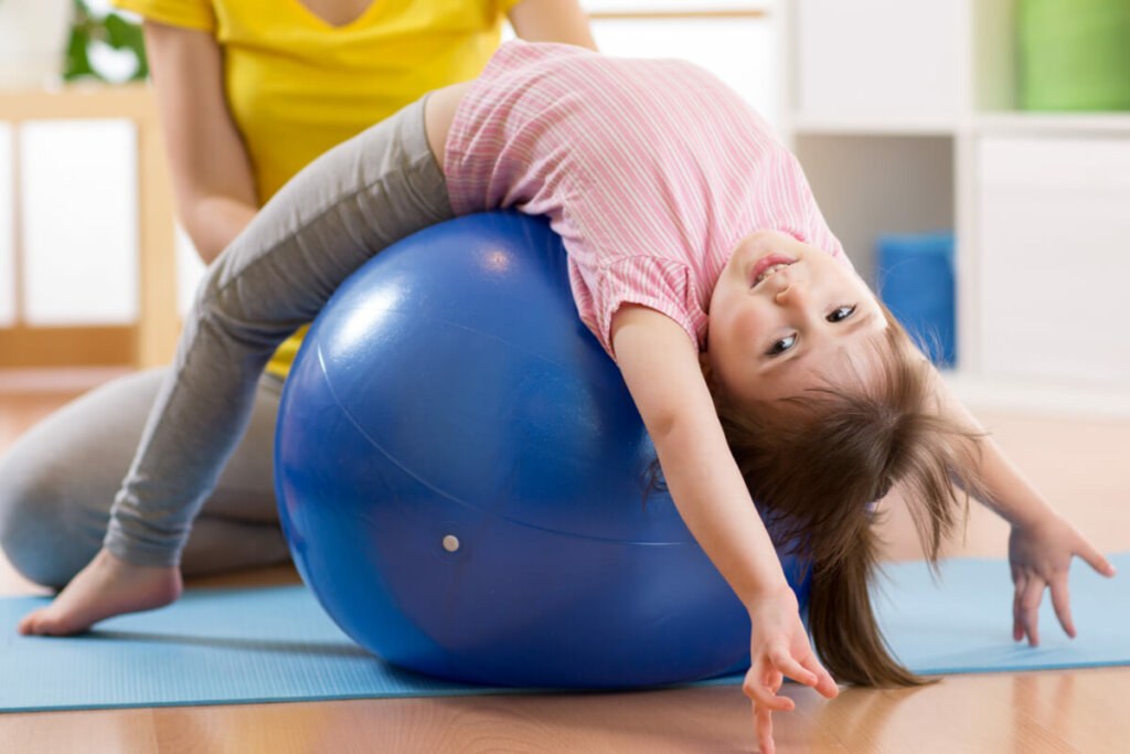 Menina em cima de uma bola azul praticando pilates