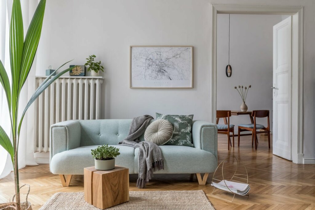 Interior da sala de estar com sofá, mesa de centro, quadro, vasos de plantas e objetos decorativos