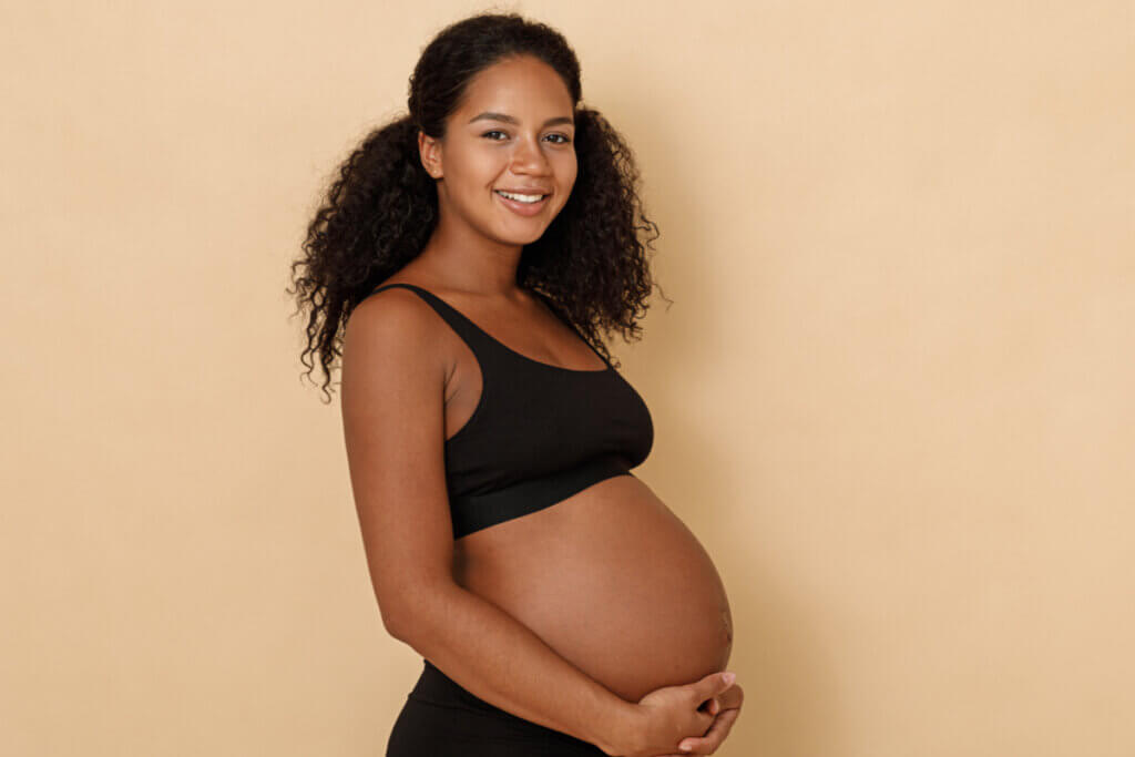 Mulher grávida sorrindo posando para foto de lado