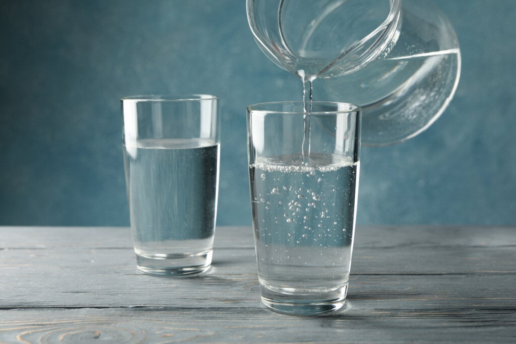 Dois copos com água e uma jarra despejando água em um dos copos
