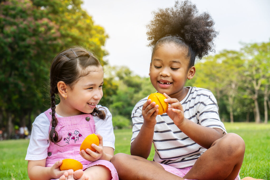 Duas meninas em um parque segurando laranja