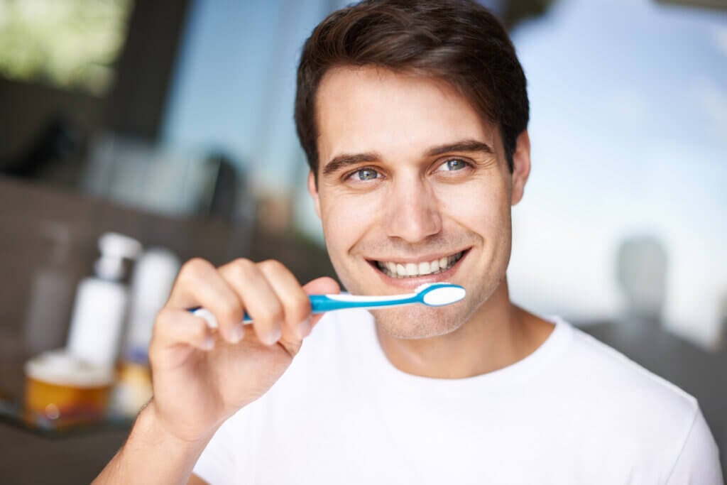 Homem sorrindo segurando escova de dente