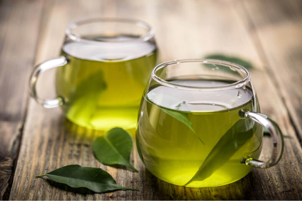 Duas xícaras com chá-verde e folha de chá dentro e ao lado
